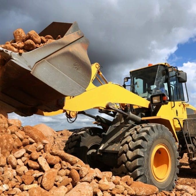 Front end loader dumping stone and sand in a mining quarry
